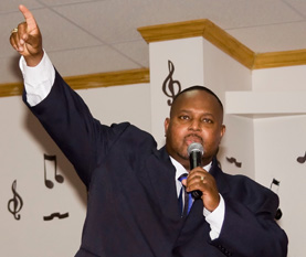 Bishop Anderson pointing upwards while talking on a mic
